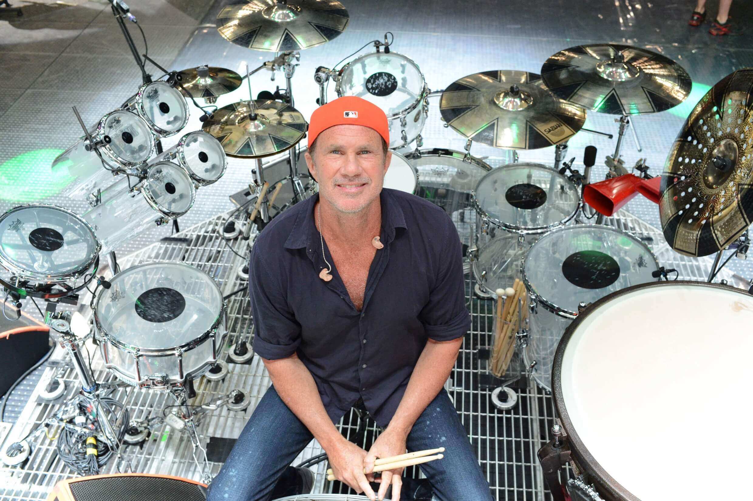 Chad Smith seated at his drum kit, poised to play with the Red Hot Chili Peppers.