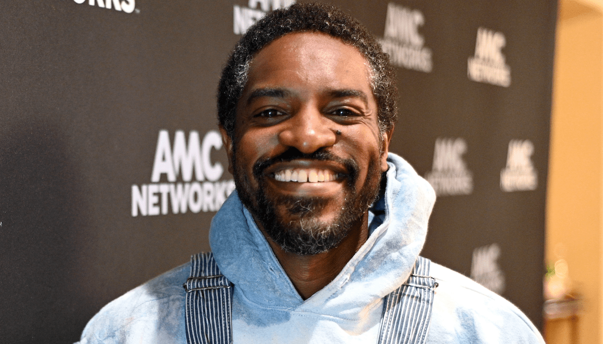 André 3000 smiling confidently on the red carpet, dressed sharplyt and exuding effortless style.