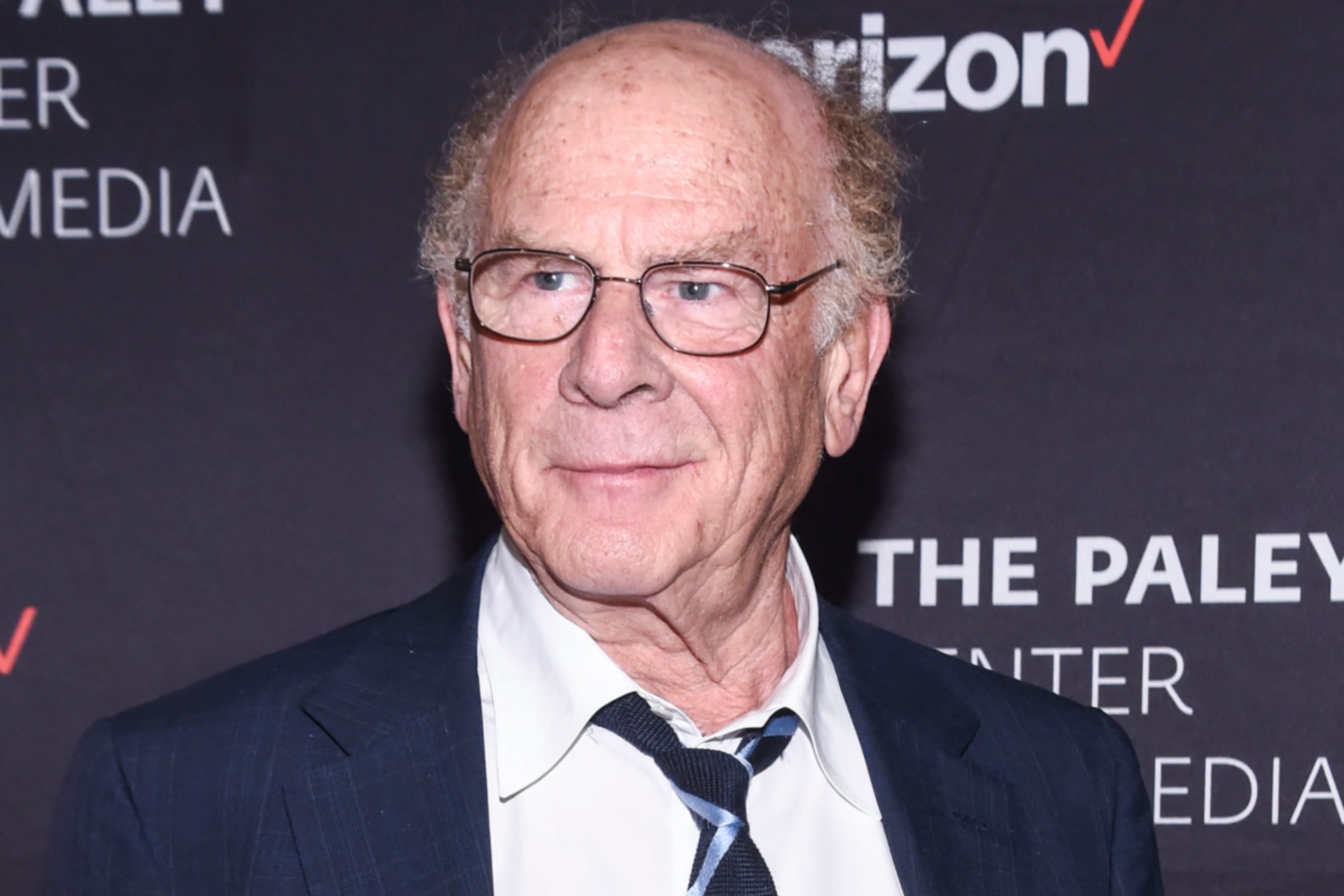 Art Garfunkel wearing a sharp suit on the red carpet, smiling confidently at a high-profile event.