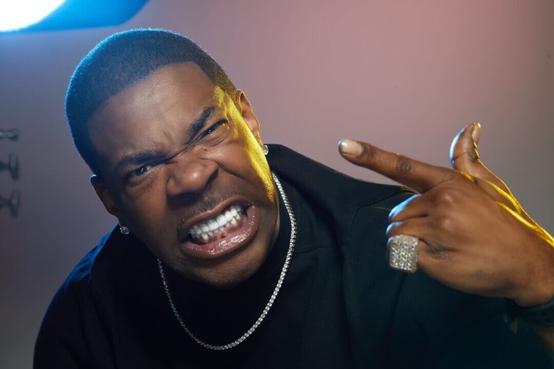 Busta Rhymes gritting his teeth and pointing with intense energy during a photo shoot.