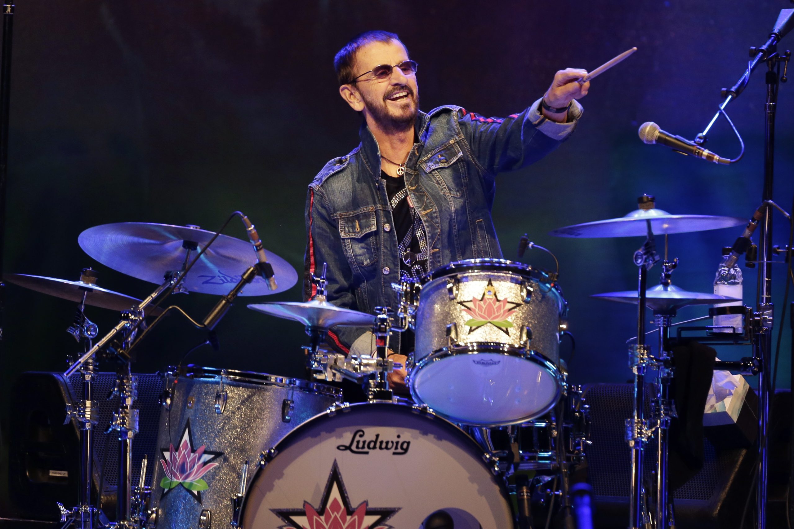 Ringo Starr playing drums passionately on stage during a live concert.