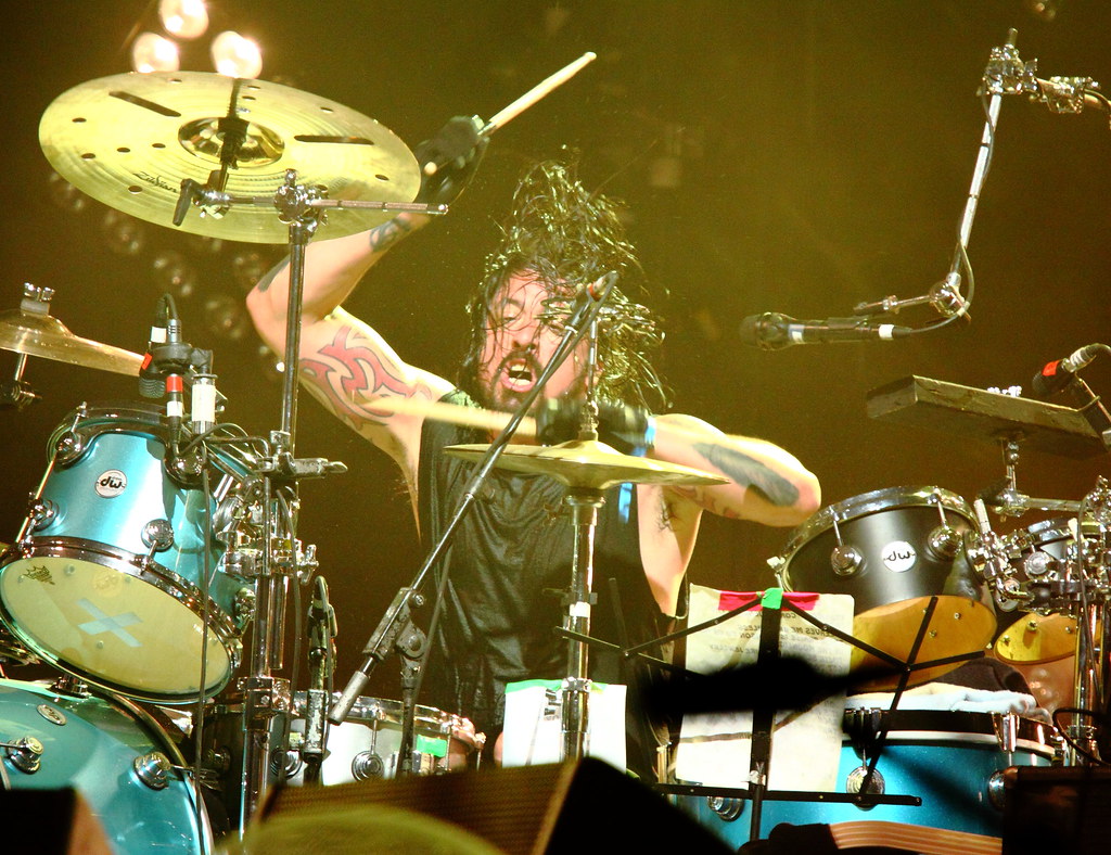 Dave Grohl mid-drum solo, captured in motion with hair flying and sticks blurred.