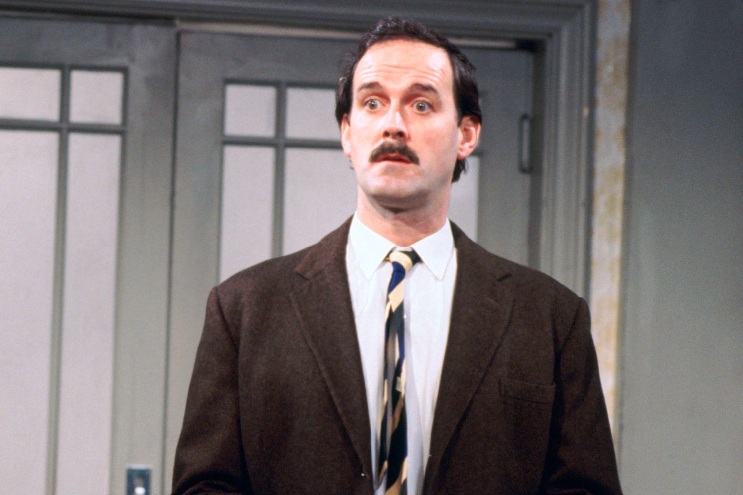 John Cleese looking surprised with wide eyes and raised eyebrows in a scene from Fawlty Towers.