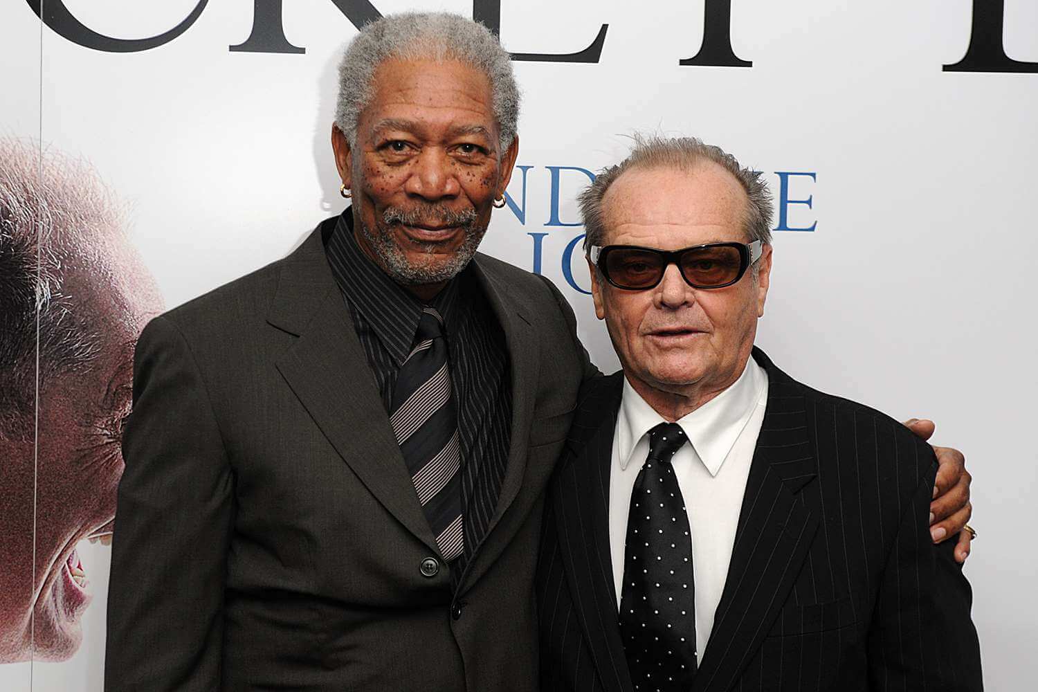 Morgan Freeman and Jack Nicholson warmly embracing each other on the red carpet at a film premiere.