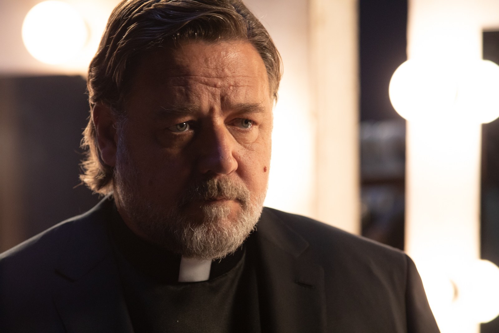 Russell Crowe portraying Father Mendoza in The Pope’s Exorcist, looking intense and focused during a supernatural confrontation.