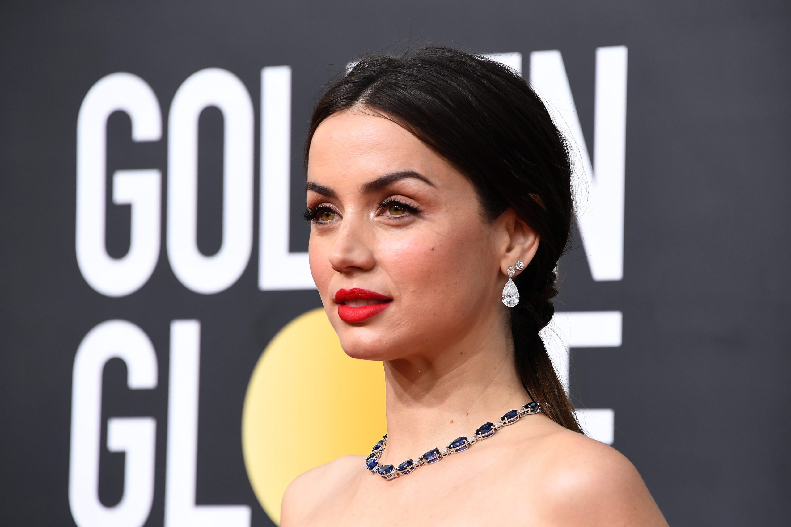 Ana de Armas posing elegantly on the Golden Globes red carpet, wearing a stunning designer gown.