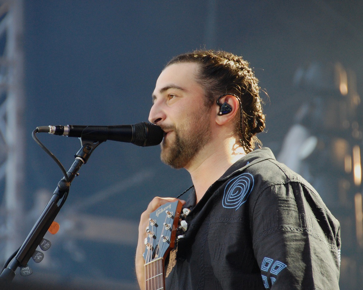 Noah Kahan performing passionately on stage at a packed music festival, guitar in hand.