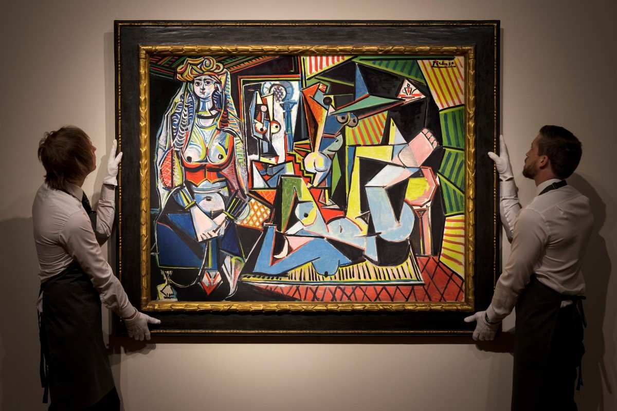 Two art handlers display Pablo Picasso’s Les Femmes d'Alger (Version O), a colorful cubist painting sold for $179.4 million at Christie’s in 2015.