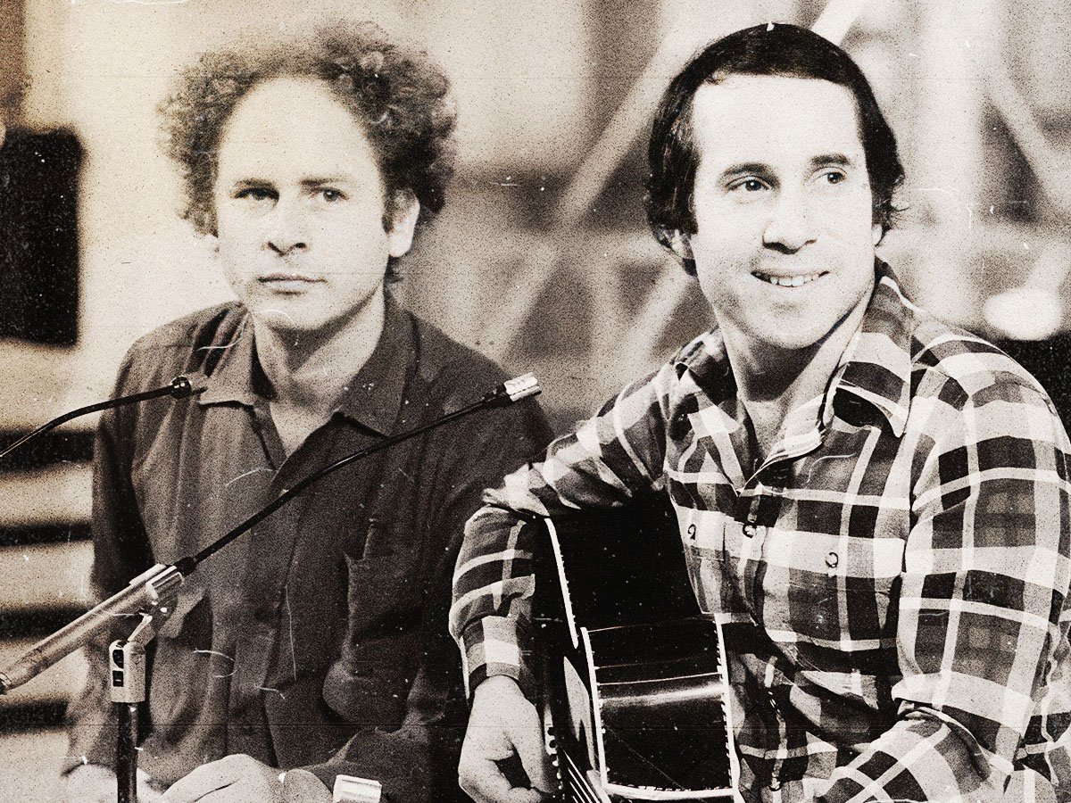 Black and white photo of Simon & Garfunkel performing live on stage, capturing their intense connection and harmony.