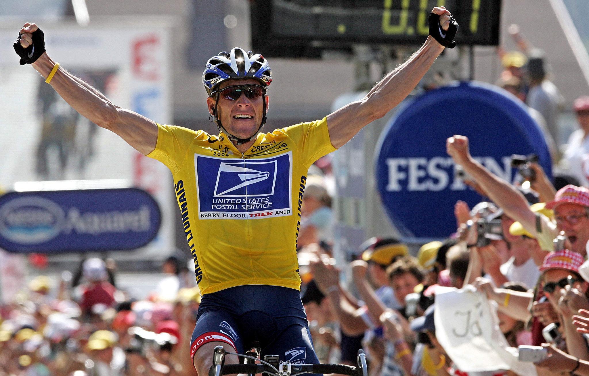 Lance Armstrong crossing the finish line at the Tour de France, arms raised in victory, wearing the yellow leader’s jersey.