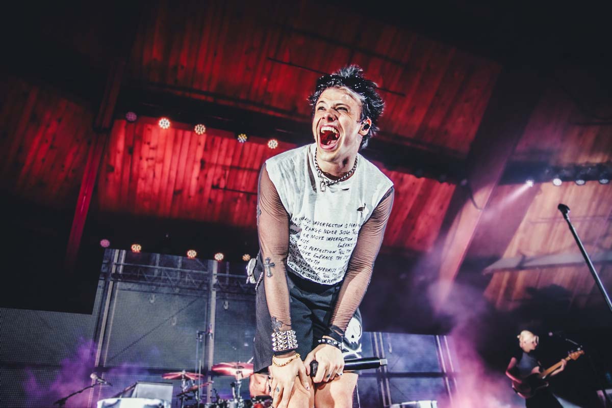 Yungblud performing on stage, smiling and engaging with fans.