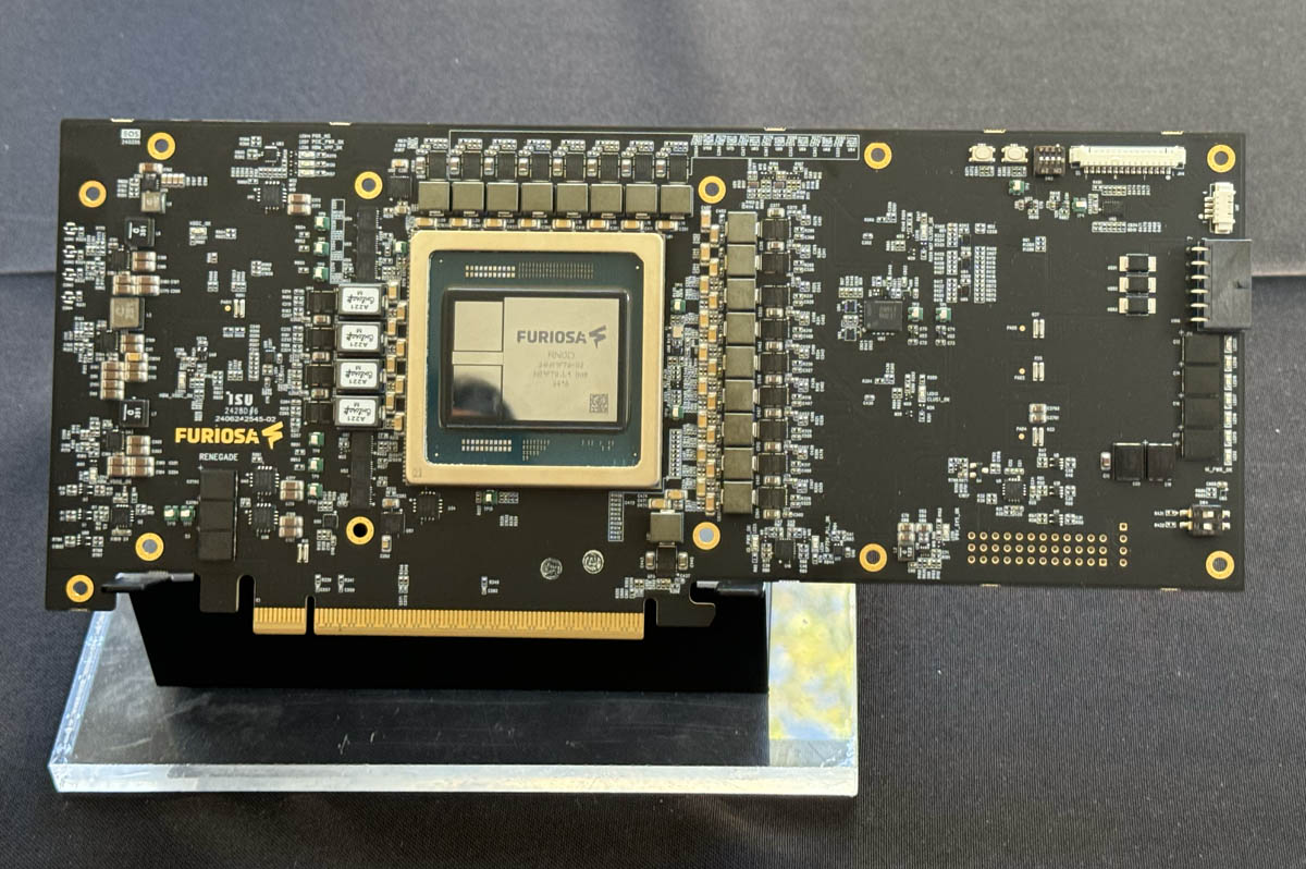 Close-up view of a FuriosaAI Renegade AI processor chip mounted on a printed circuit board (PCB), showcasing electronic components and connectors.