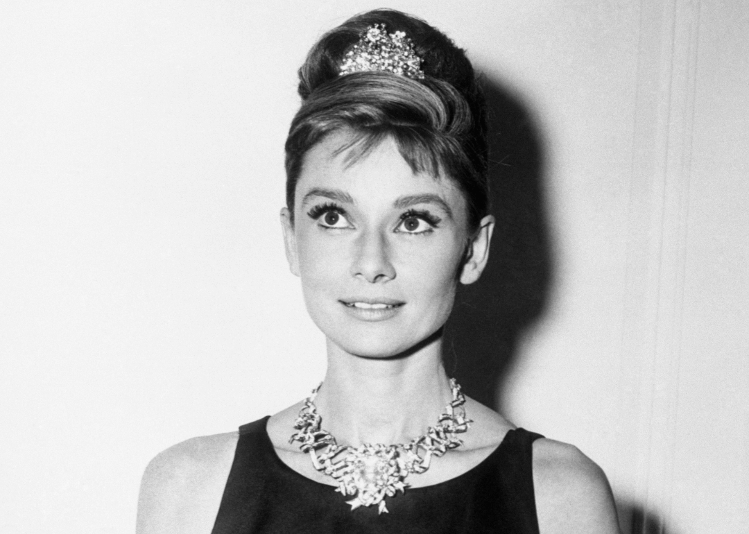 Audrey Hepburn elegantly dressed in a black gown and sparkling tiara at a formal event.