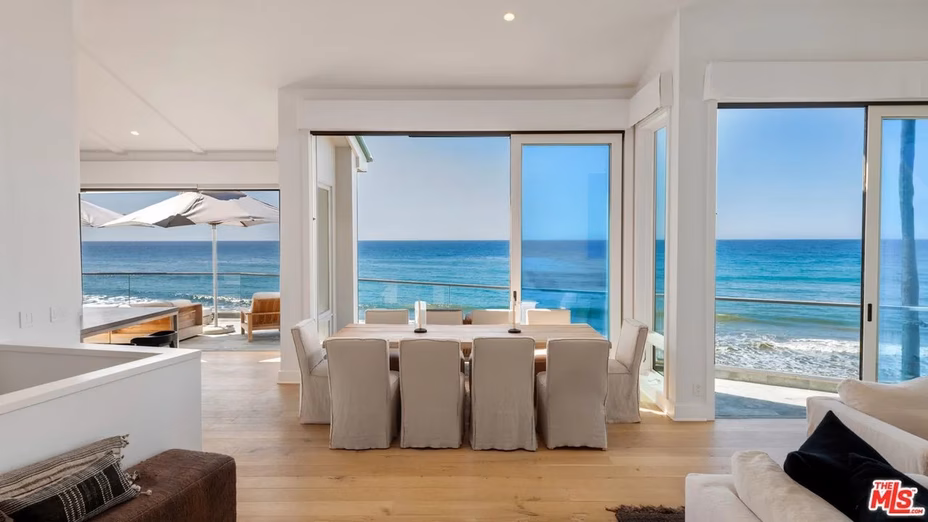 Stylish dining room featuring a large table, modern decor, and expansive windows showcasing stunning ocean views.