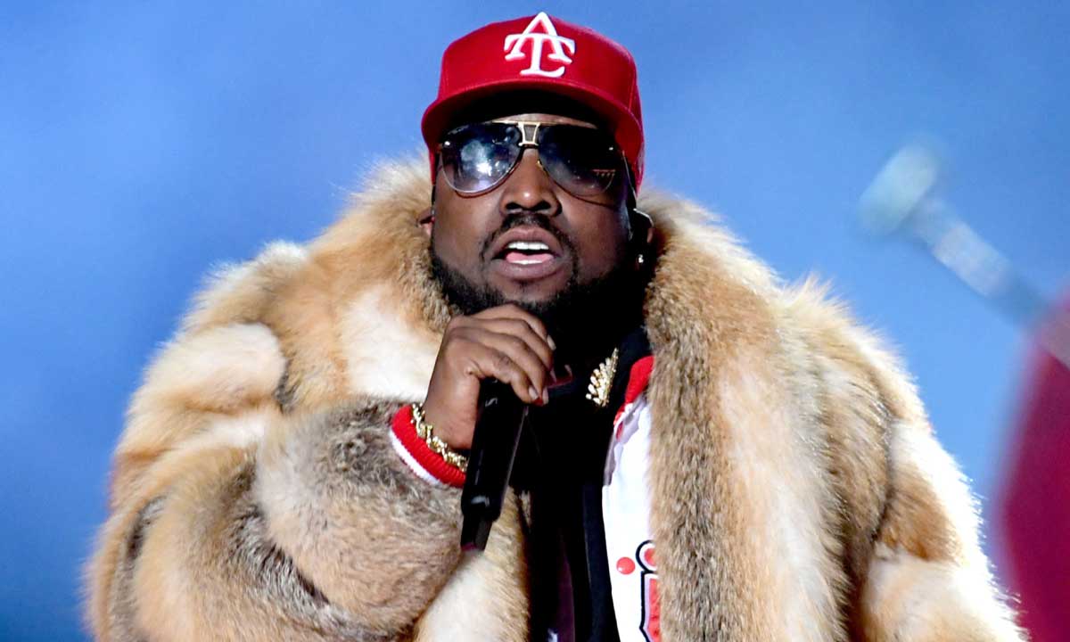 Big Boi performing live on stage in a dramatic fur coat, exuding charisma and Southern swagger under the spotlight.