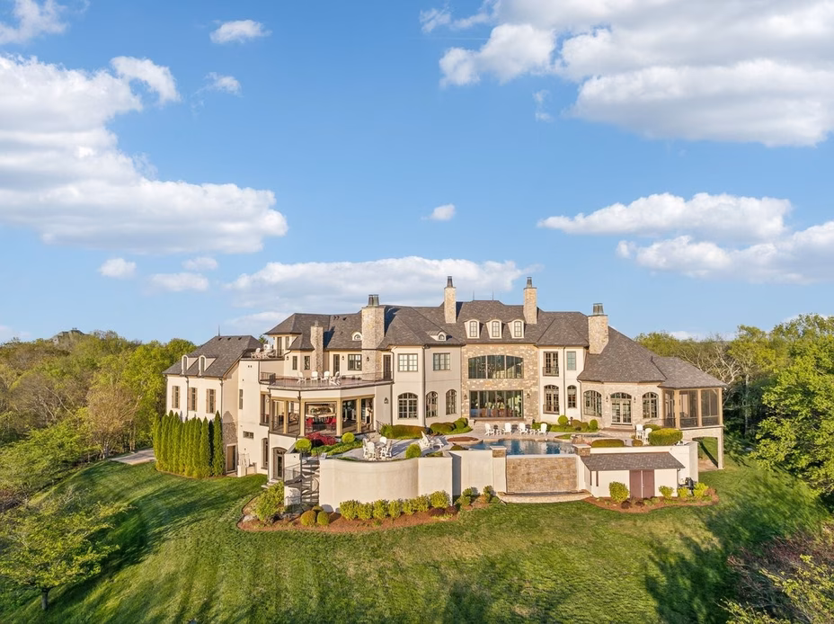 The grand exterior of Dave Ramsey’s Tennessee estate, showcasing a sprawling chateau-style mansion atop a scenic hill.