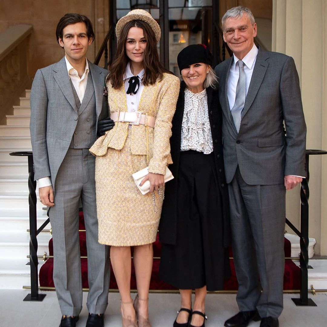 Keira Knightley pictured with her parents and husband, all smiling together at a public event.