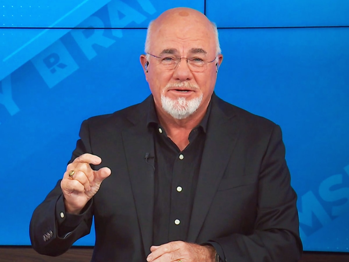 Dave Ramsey smiling and gesturing animatedly during a live recording of his radio show.