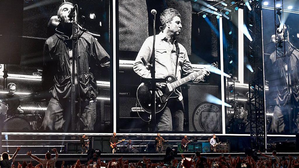 Oasis performing live on stage in Cardiff in 2025, kicking off their reunion tour with an energetic crowd.