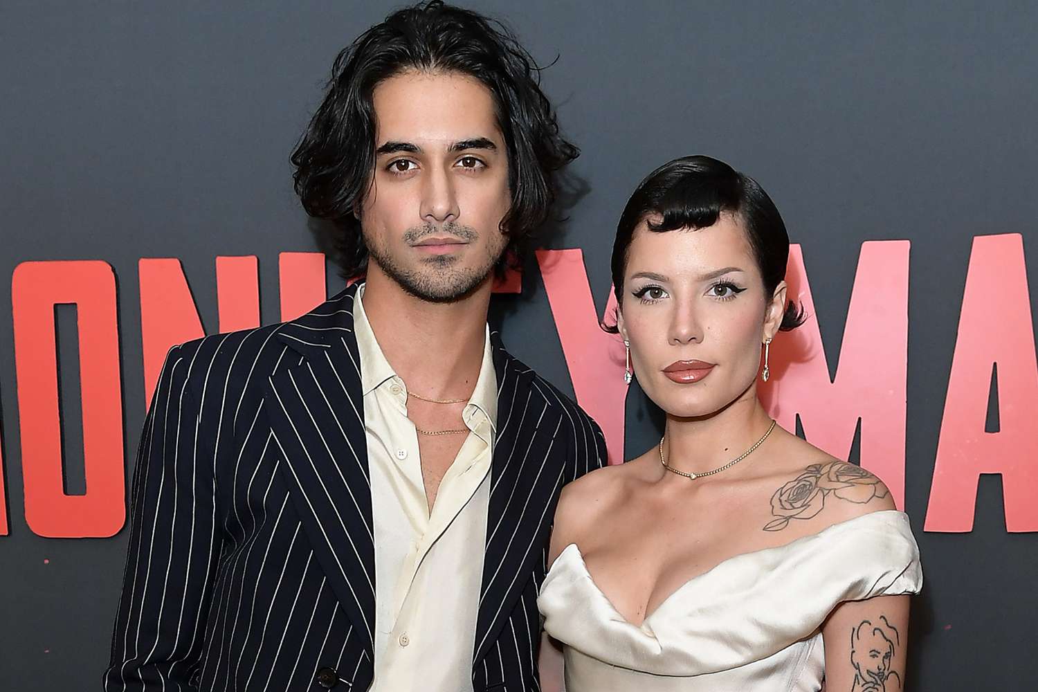 Halsey and her fiancé smiling together while posing on the red carpet, dressed elegantly for the event.
