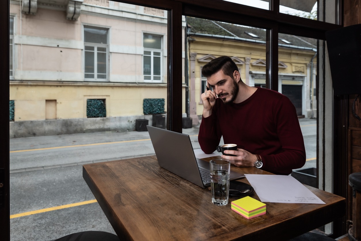young business man sitting in the coffee shop during the lunch break drinking coffee and work on the laptop computer. freelancer business person working on the new project for foreign company.