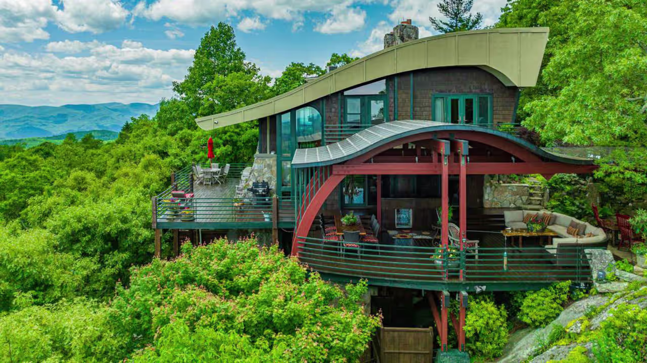 Exterior view of Burt Reynolds’ former treehouse-style home in the Blue Ridge Mountains, surrounded by forest and mountain views.