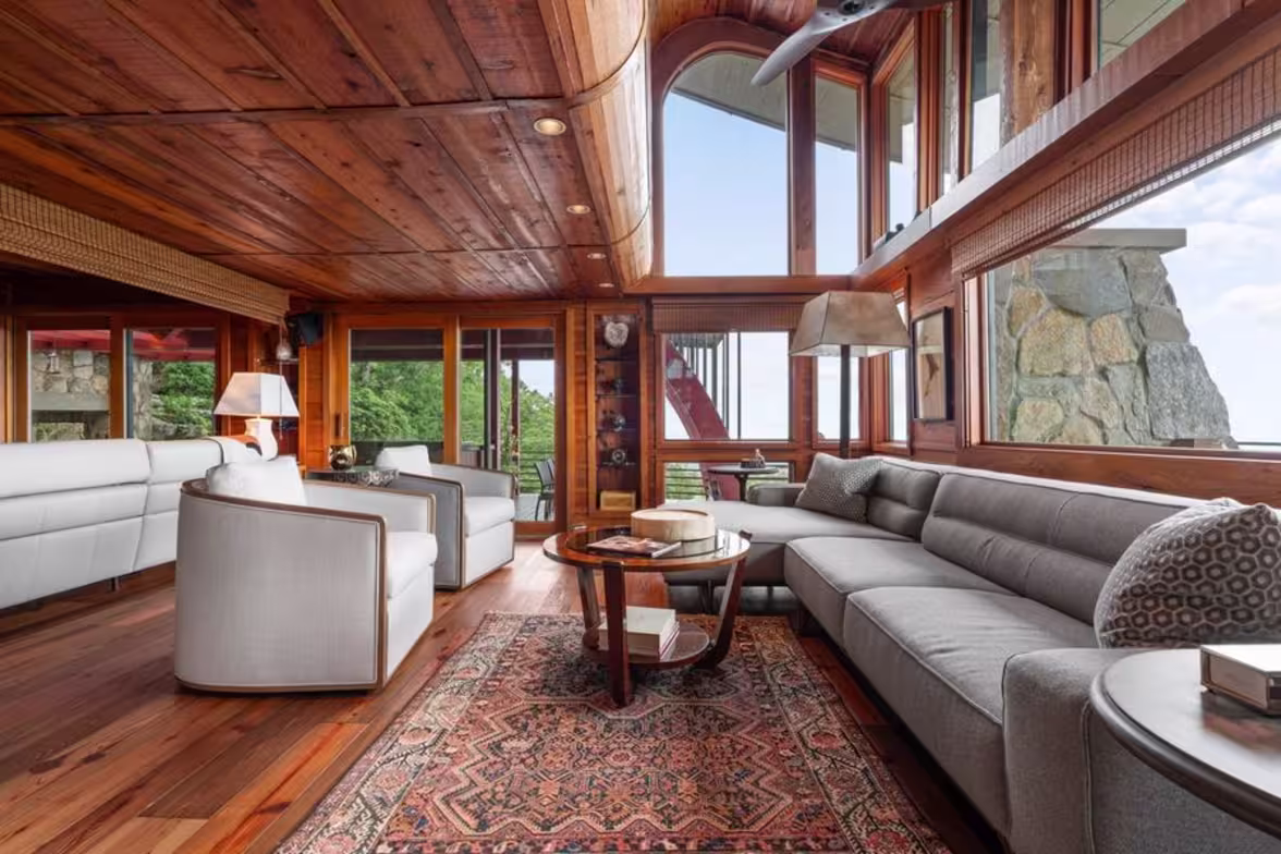 Sunken living room in Burt Reynolds’ former Blue Ridge Mountains home with curved wood ceilings and a stone fireplace.