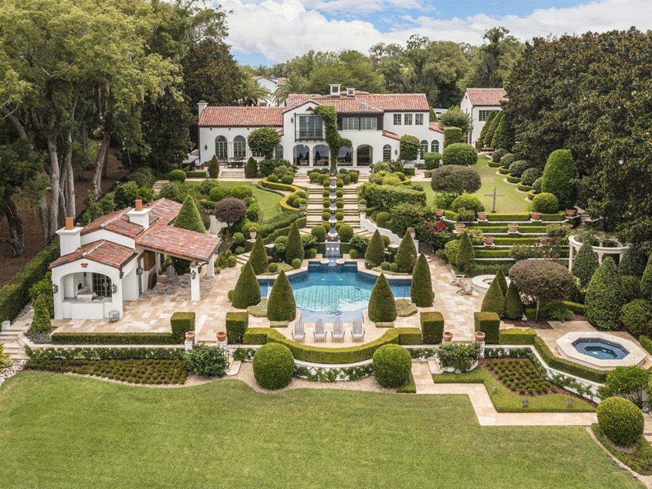 Exterior view of John Morgan’s luxurious Florida estate surrounded by lush greenery and palm trees.