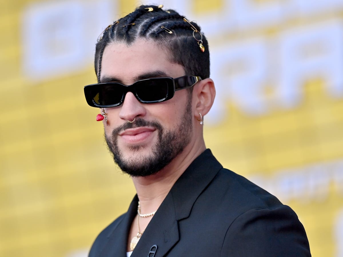 Bad Bunny smiling brightly while posing on the red carpet at a high-profile event.