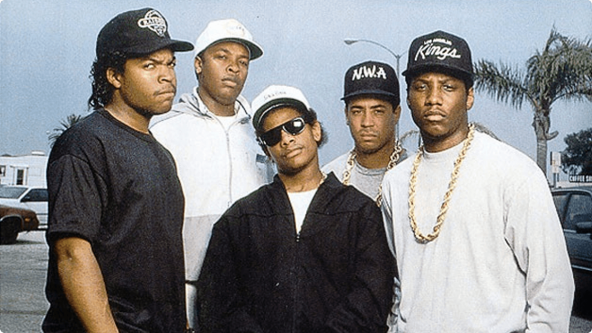 N.W.A standing together at the height of their fame, wearing iconic '90s West Coast streetwear, exuding confidence and attitude.
