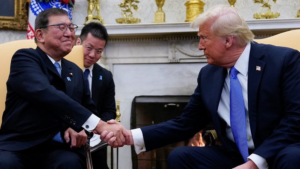 Donald Trump and Japanese Prime Minister Shigeru Ishiba shaking hands in the Oval Office after announcing a historic $550 billion trade agreement.