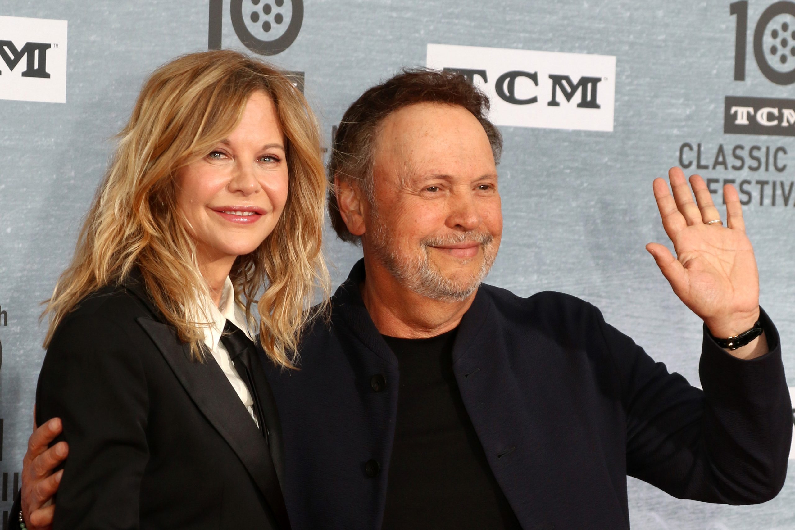 Meg Ryan and Billy Crystal smiling together on the red carpet at a film event, dressed in formal evening wear.