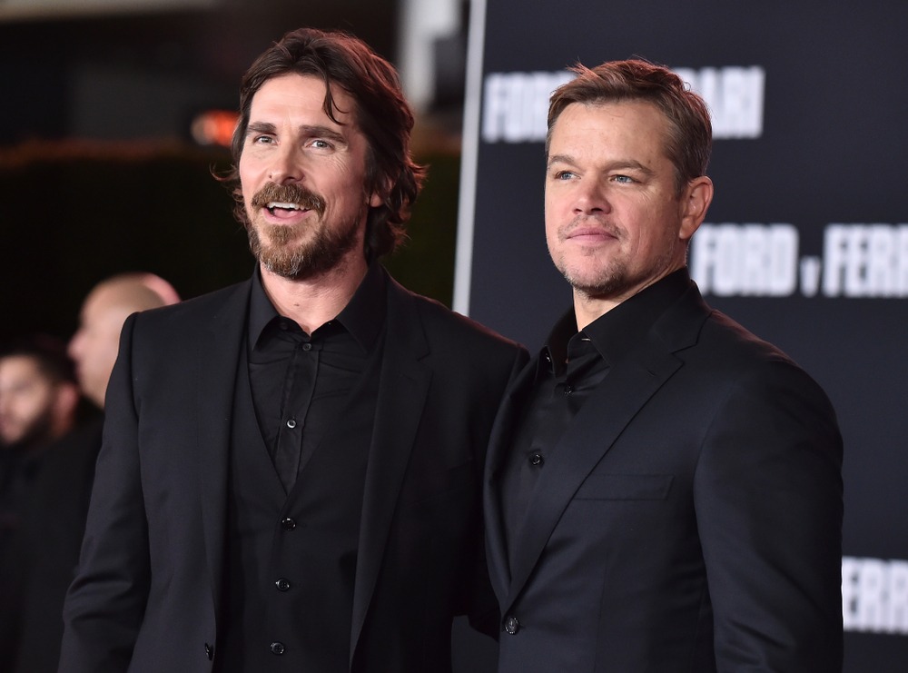 Christian Bale and Matt Damon smiling together on the red carpet at the premiere of Ford v Ferrari.