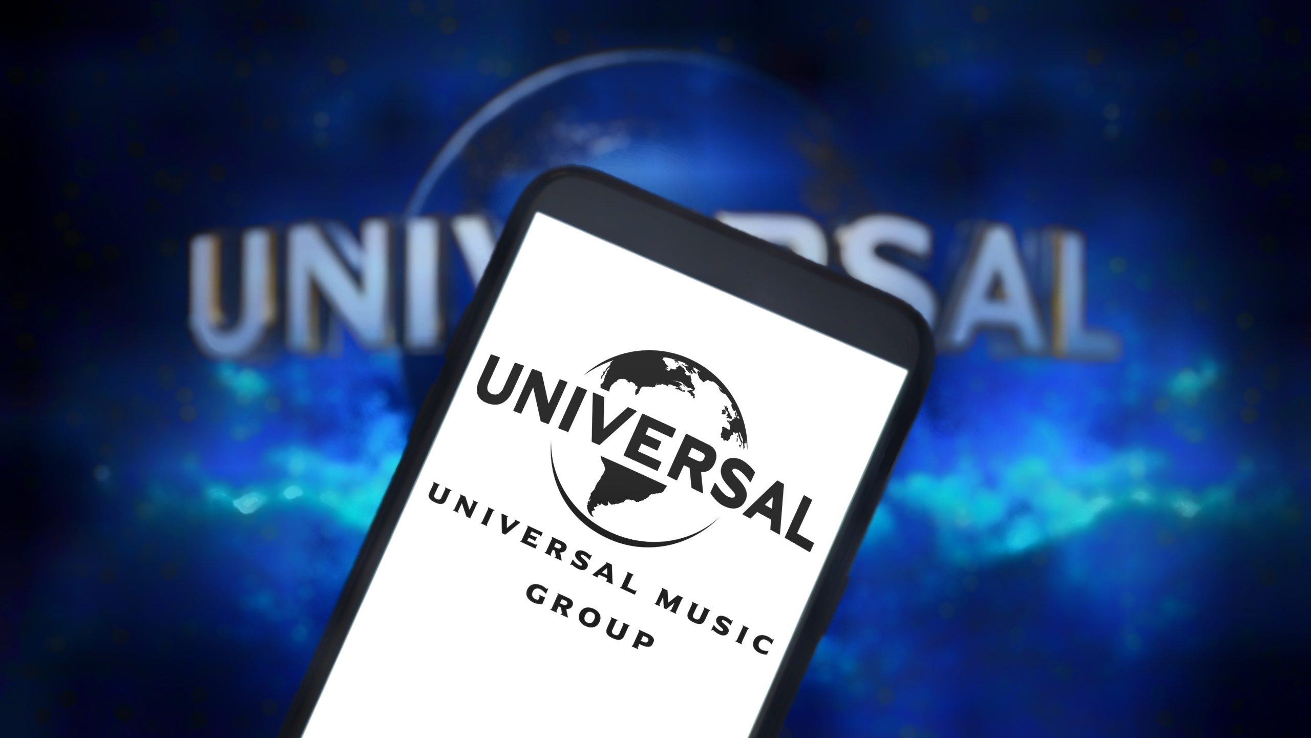 A smartphone screen displaying the Universal Music Group (UMG) logo against a dark background.