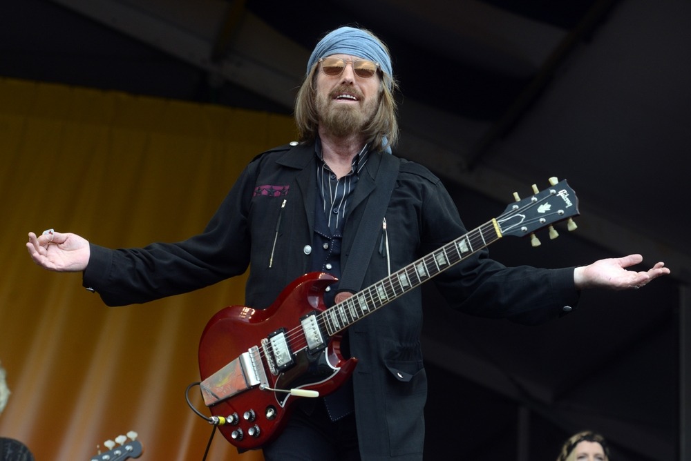 Tom Petty performing live on stage with his guitar under vibrant lights.