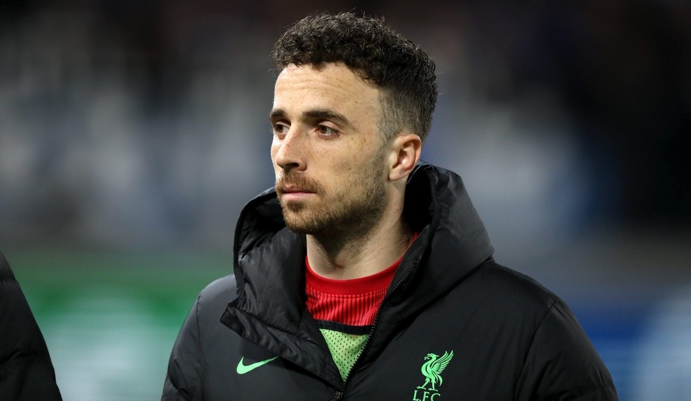 Diogo Jota wearing a Liverpool coat, preparing for a match with focused determination.