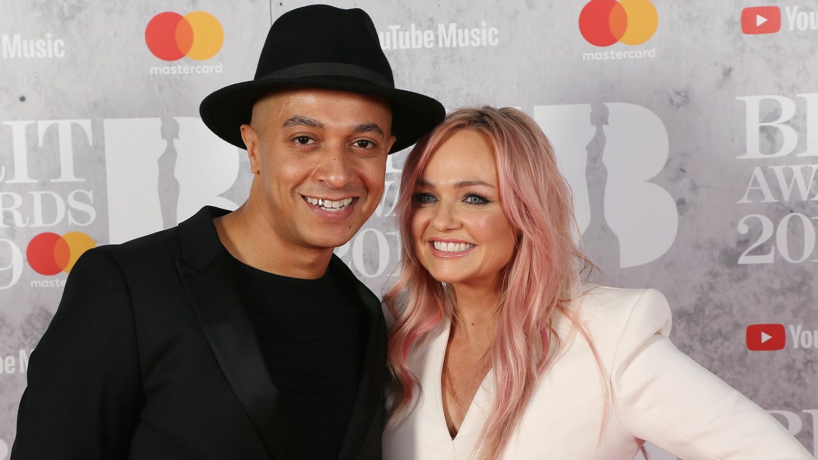 Emma Bunton and husband Jade Jones posing together on the red carpet, both dressed elegantly.