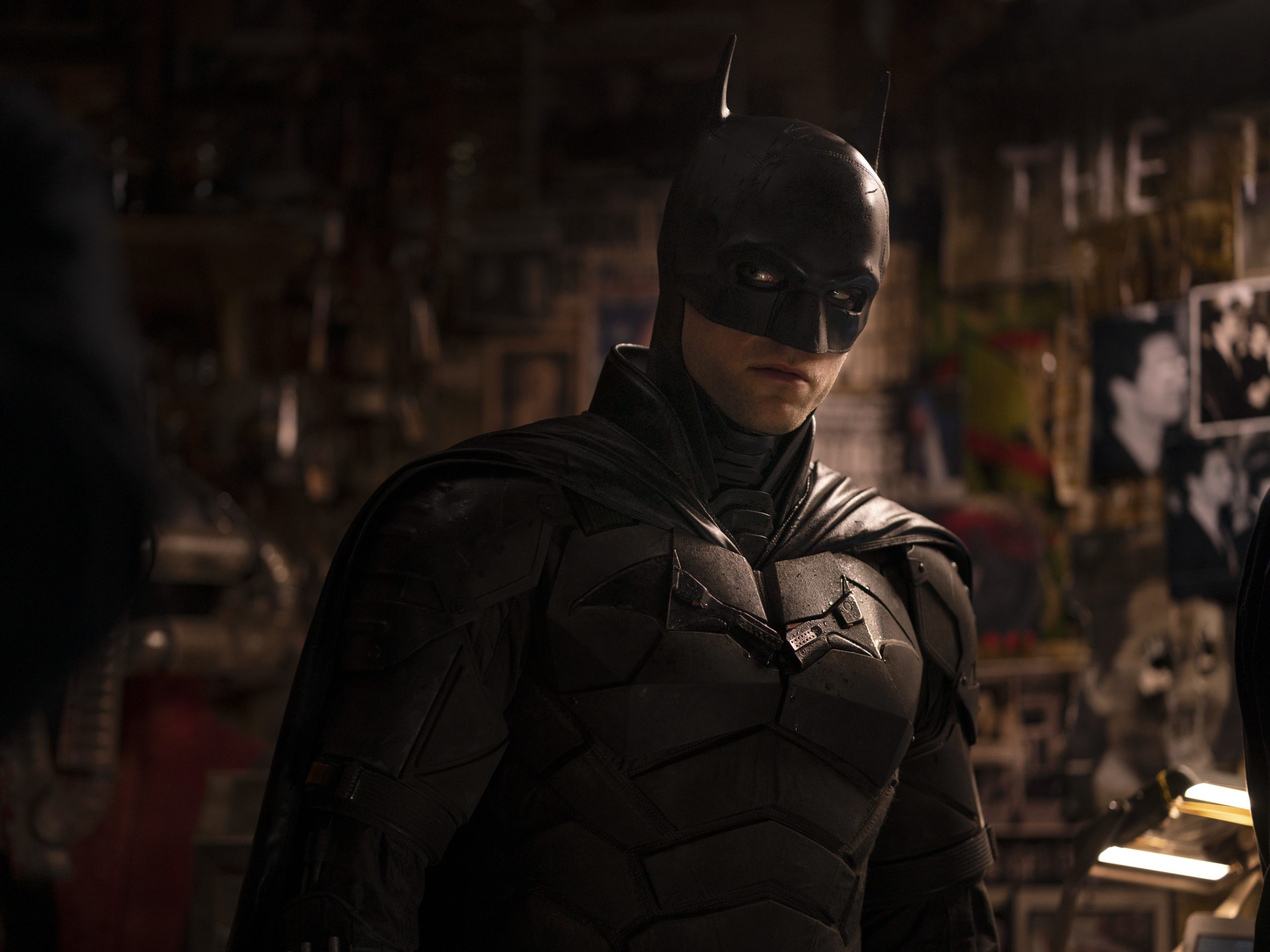 Robert Pattinson as Batman, wearing the iconic dark suit and mask with a brooding expression.