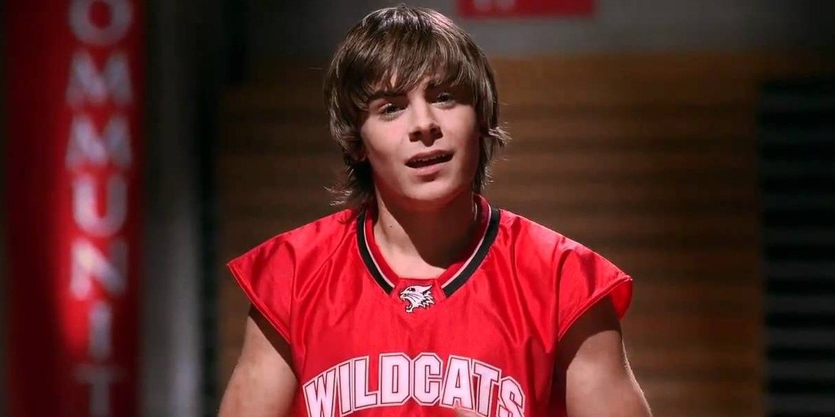 Zac Efron as Troy Bolton in High School Musical, performing on stage with a basketball in hand.