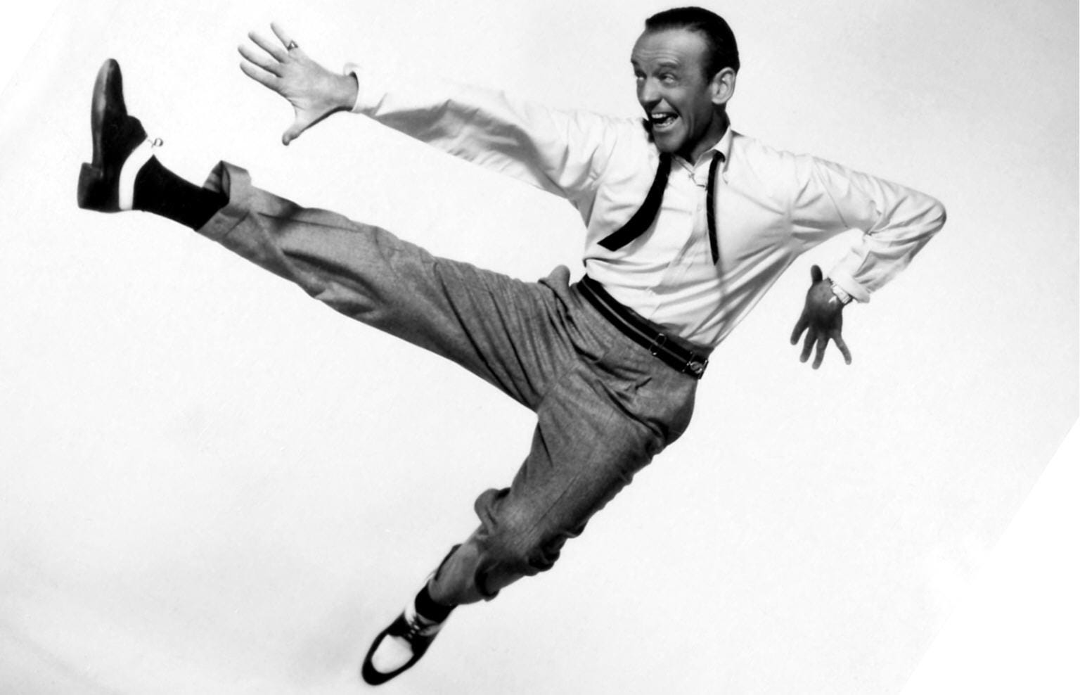 Fred Astaire mid-jump during a dance routine, showcasing his graceful and athletic style.
