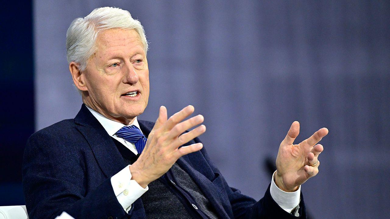 Former U.S. President Bill Clinton speaking on stage, gesturing with his hands during a public event.