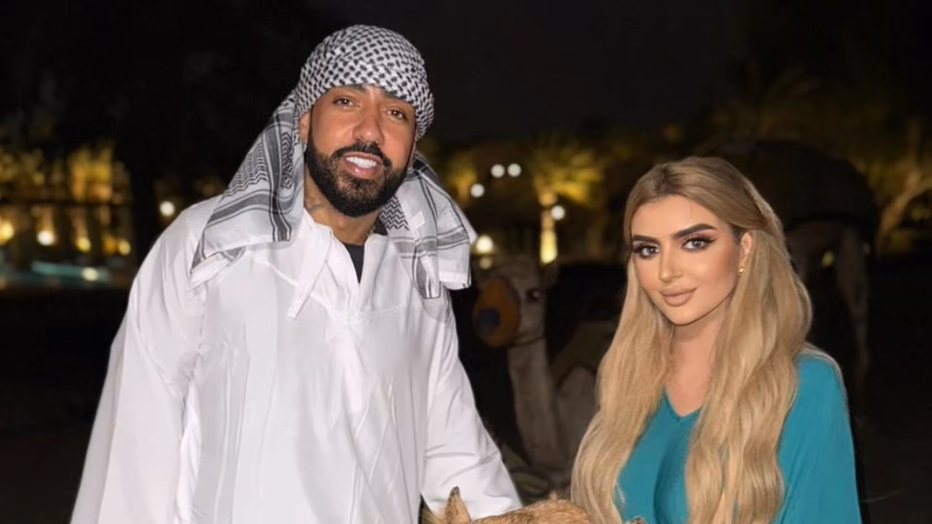 French Montana and Dubai Princess Sheikha Mahra smiling at the camera together, showing their engagement and joyful moment.