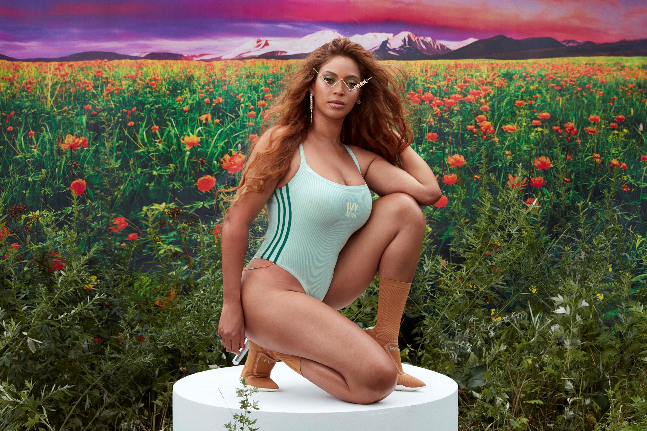 Beyoncé modeling Ivy Park swimwear on a podium during a professional photo shoot, showcasing the collection’s athletic and stylish designs.