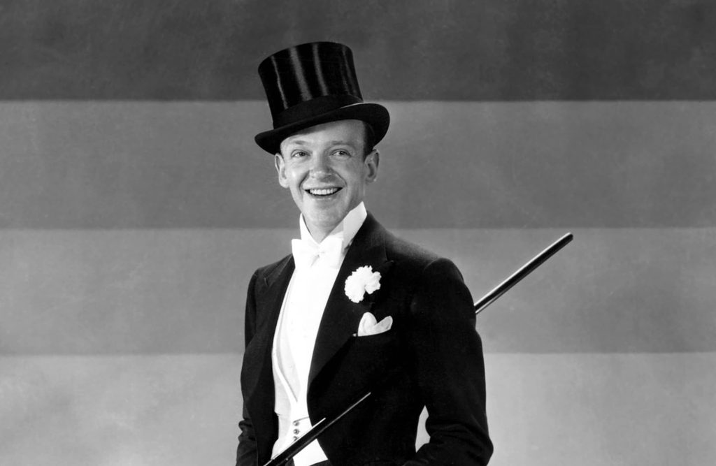 Fred Astaire wearing a top hat and holding a cane, striking a classic dance pose.