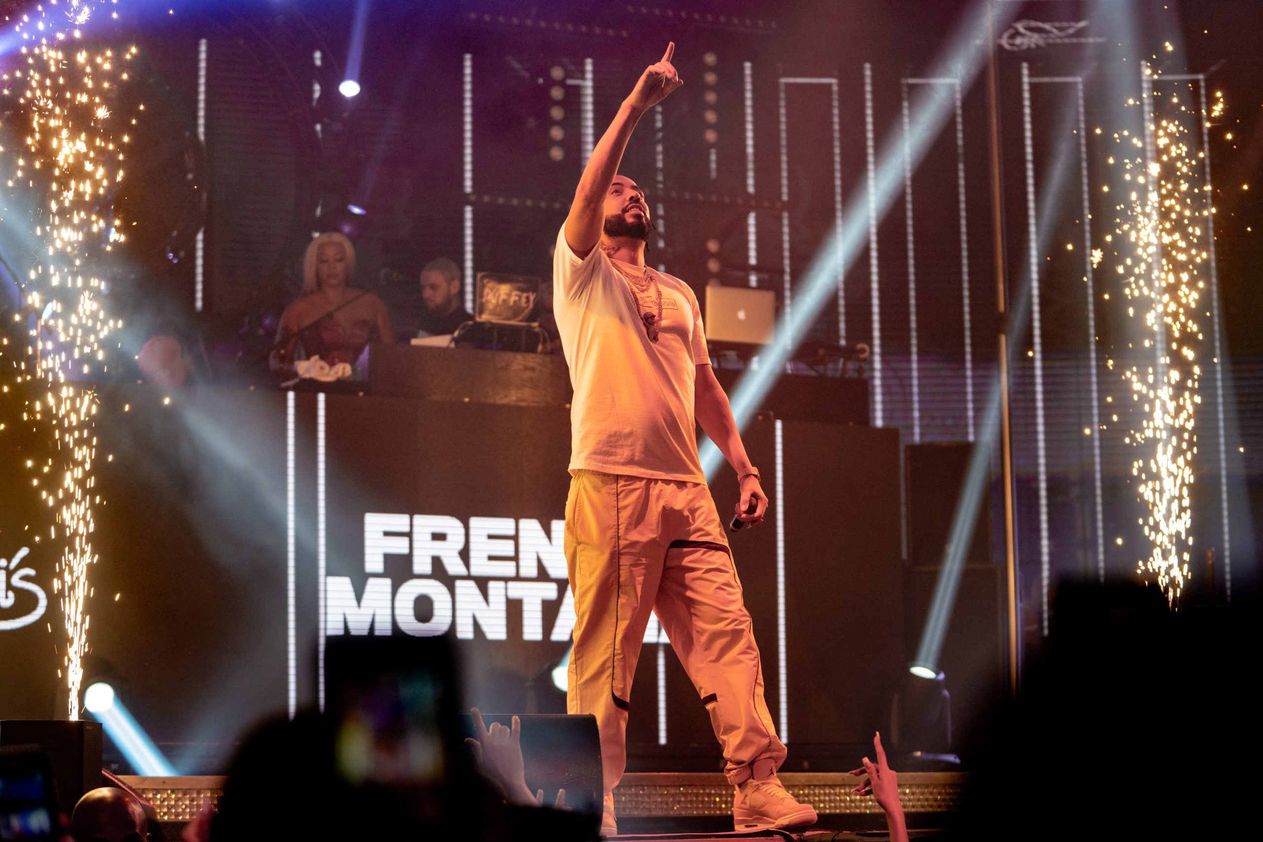 French Montana performing energetically on stage in front of a cheering crowd.