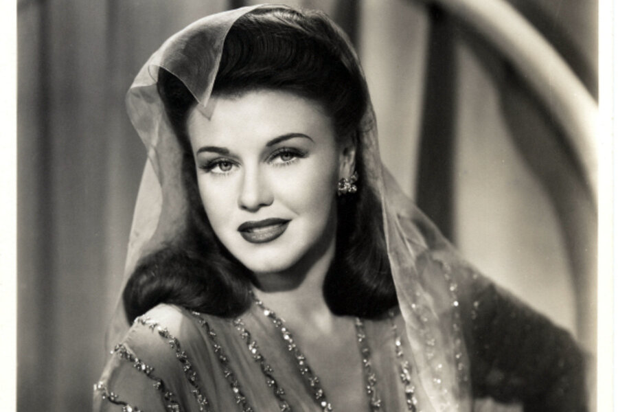 Ginger Rogers dressed in a dazzling bejeweled outfit with a matching ornate headpiece, radiating glamour.