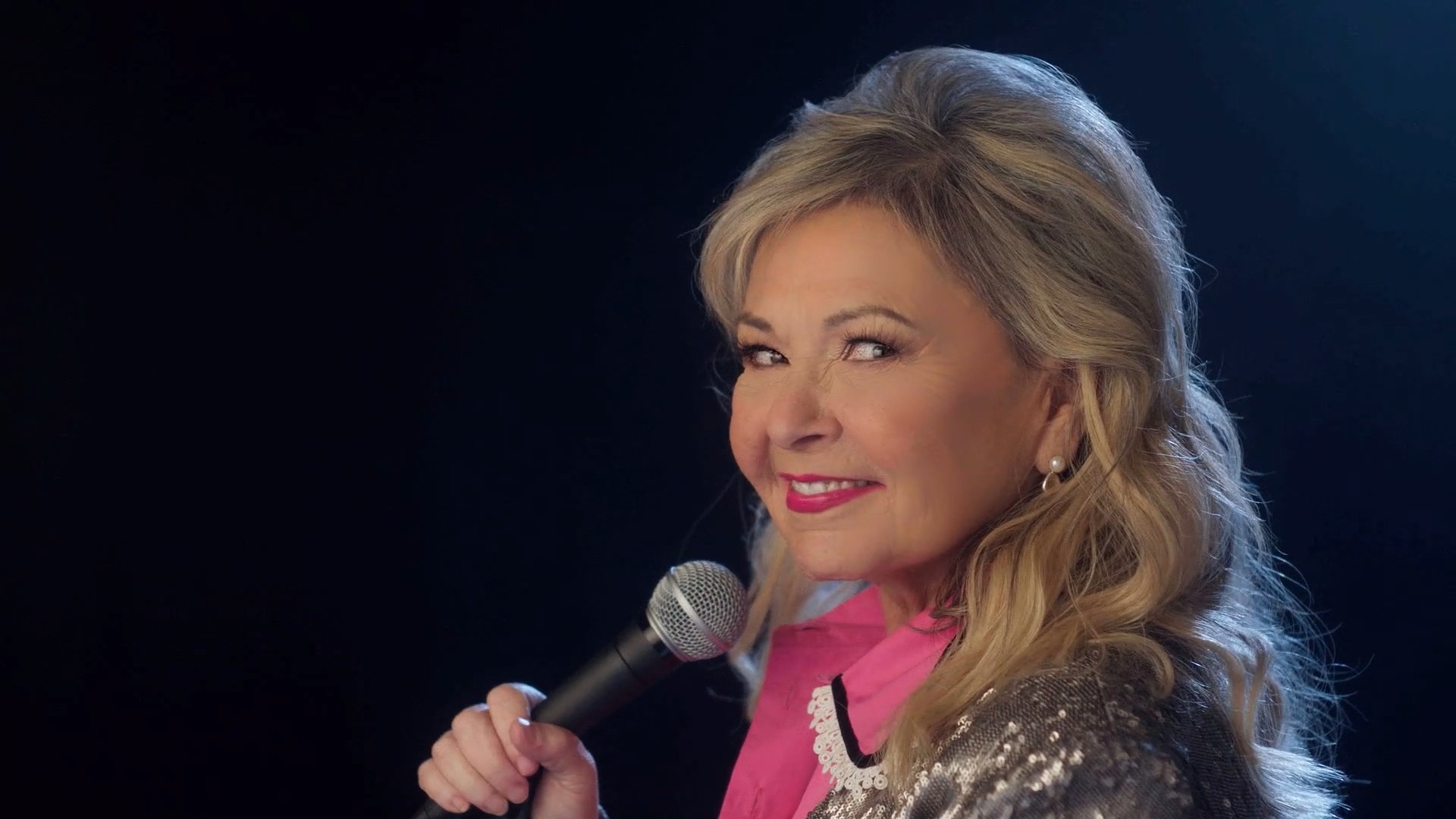 Roseanne Barr holding a microphone, preparing to step on stage for a performance.
