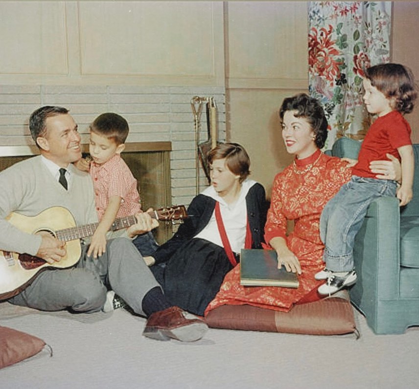 Shirley Temple sitting with her husband and children in their family home.