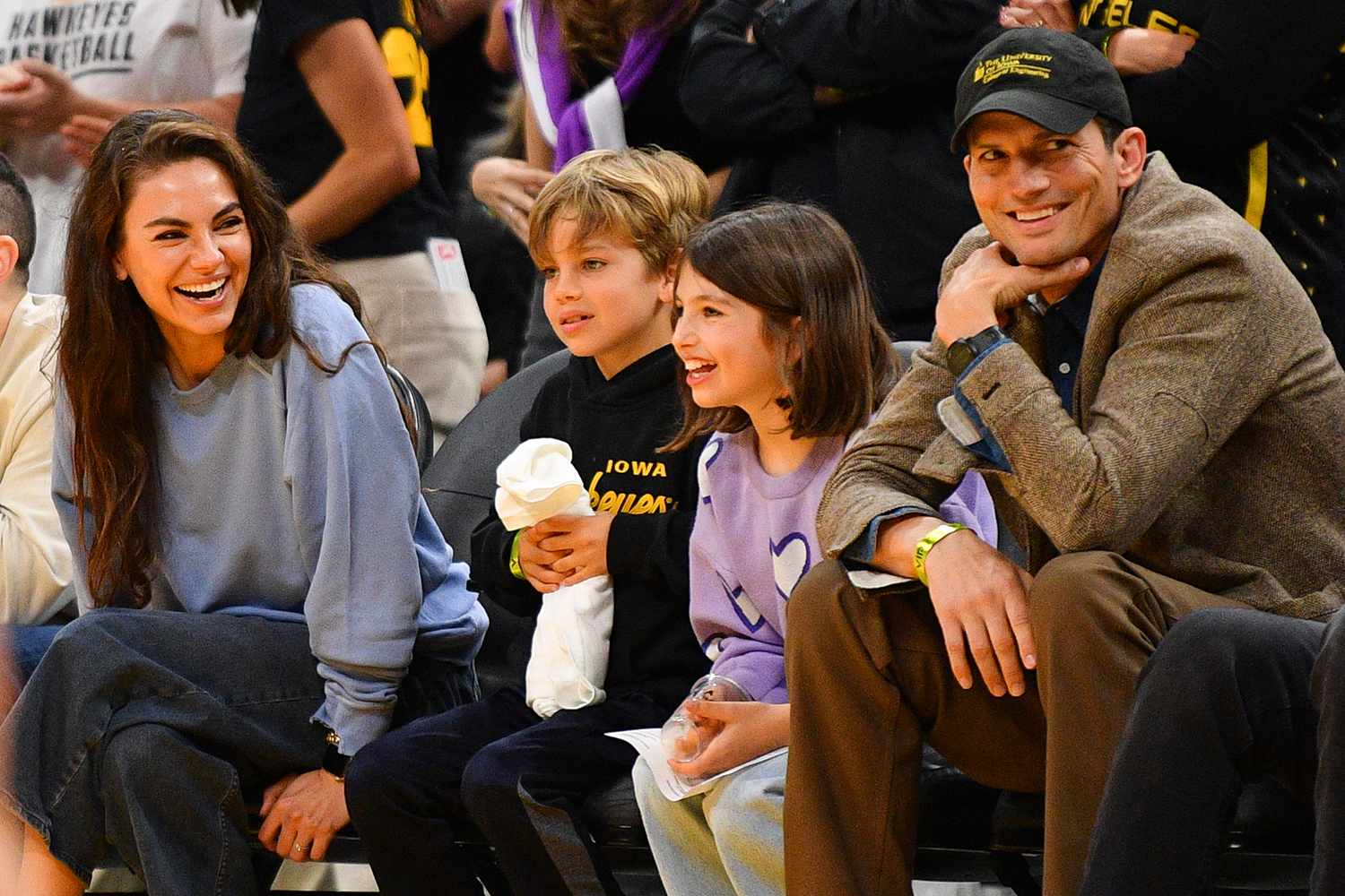 Mila Kunis sitting courtside with her family, enjoying a basketball game together.