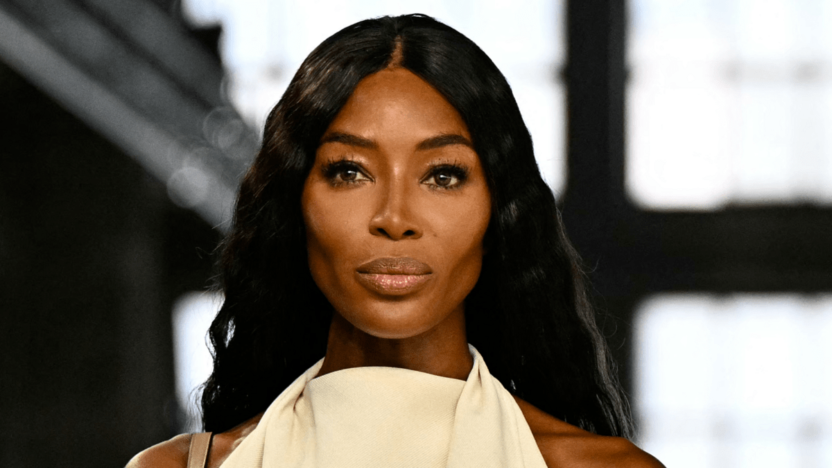 Naomi Campbell posing gracefully in a cream designer dress, exuding elegance and sophistication.
